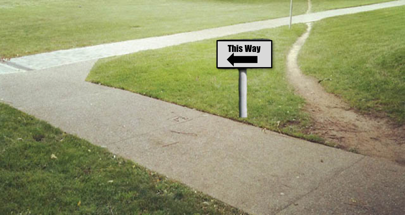 A well-worn dirt track cutting across a grassy area, showing where people have created a shortcut instead of following the designed path.